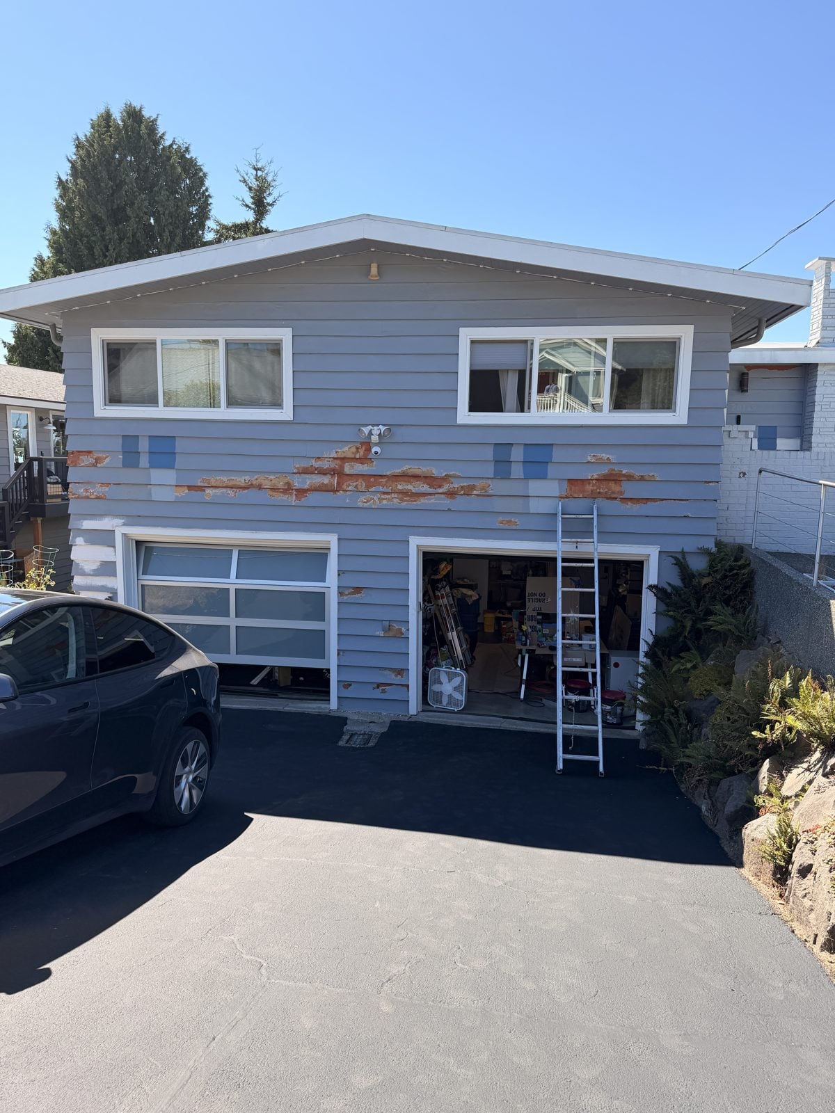 Two-story home with peeling, failing paint above the garage