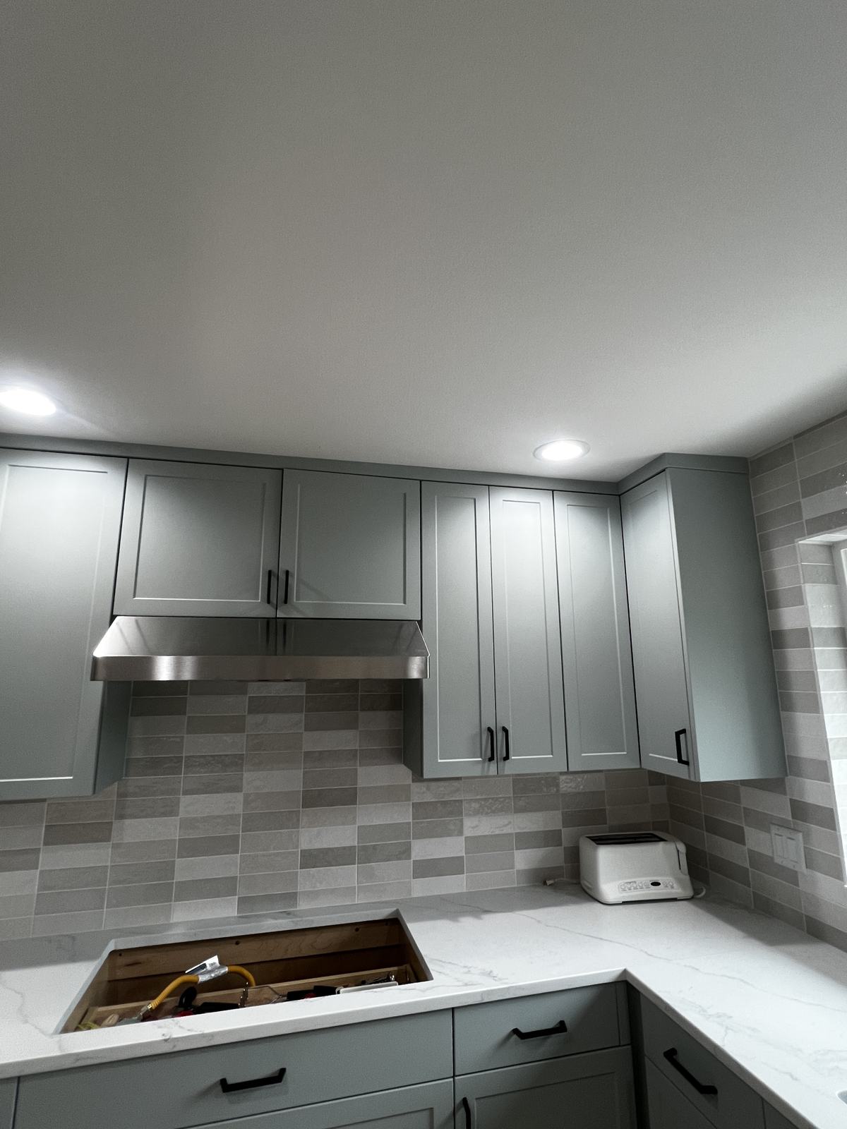 Sage green painted upper and lower cabinets around the range in a Monroe kitchen