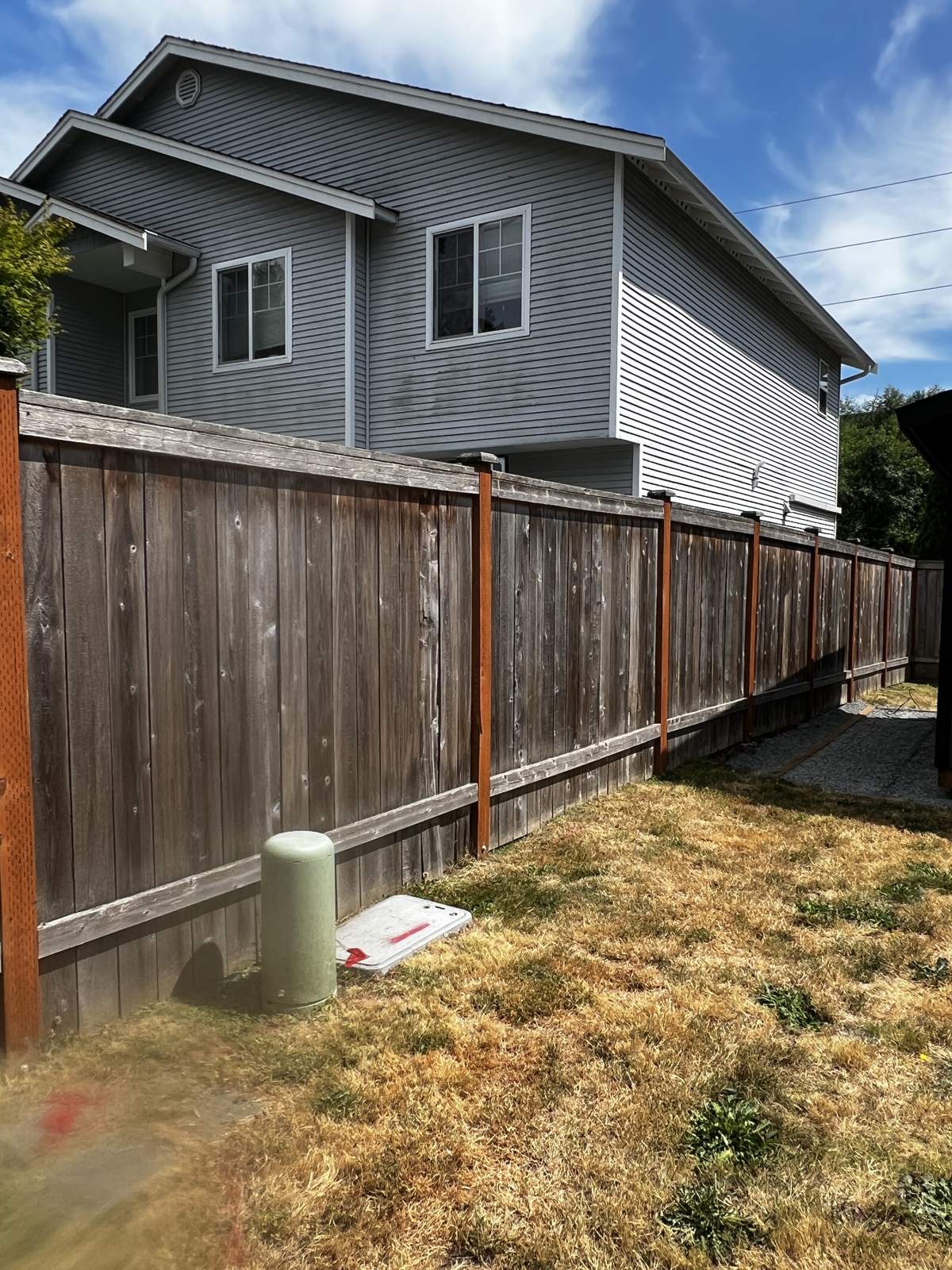 Weathered gray fence in a Mukilteo backyard before staining