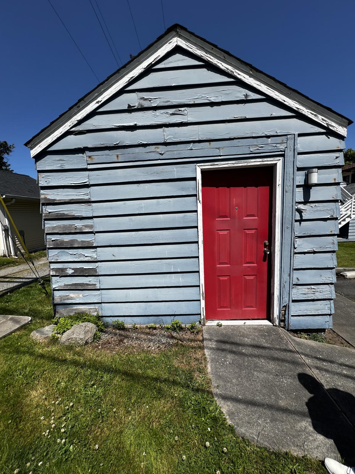 Peeling paint on a commercial outbuilding with a red door