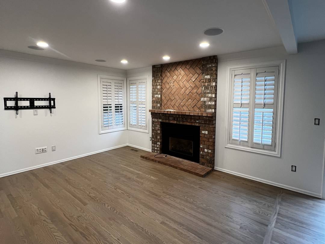 Family room with fresh white walls and a brick fireplace after an interior repaint