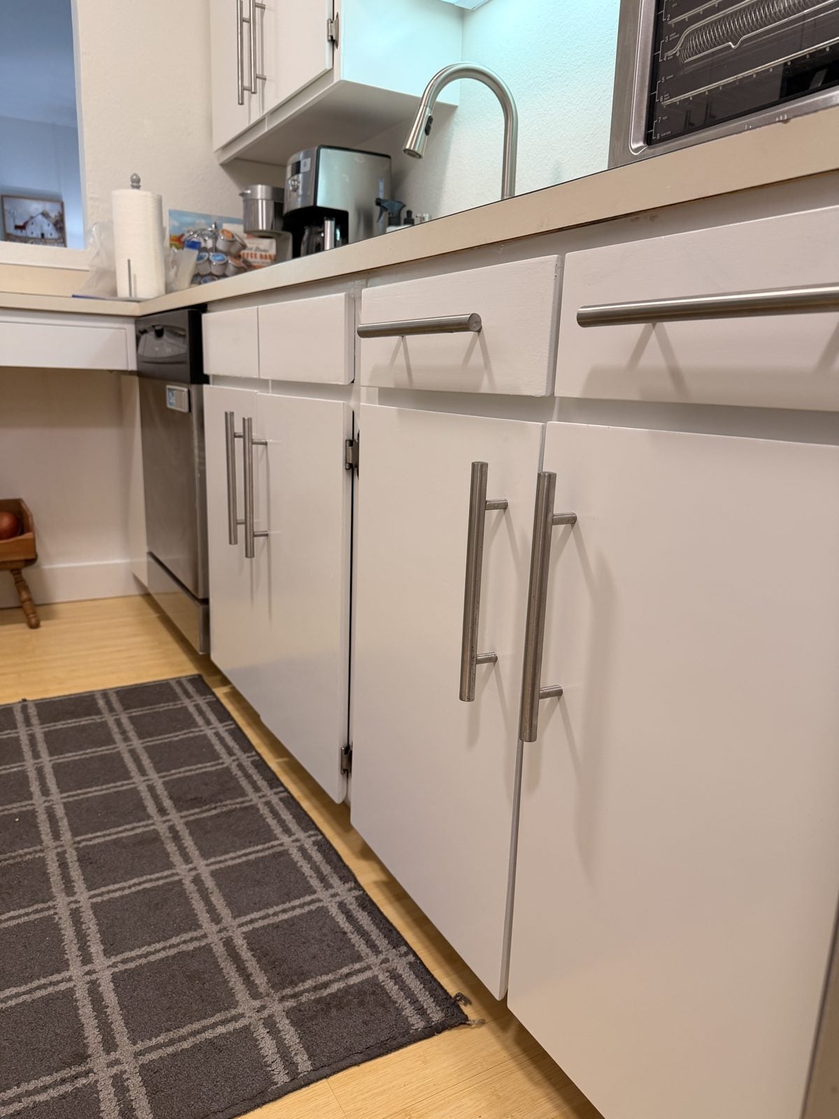 Painted white lower kitchen cabinets with long stainless pulls