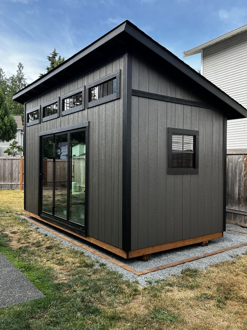 The same Mukilteo backyard studio painted black with a cedar base