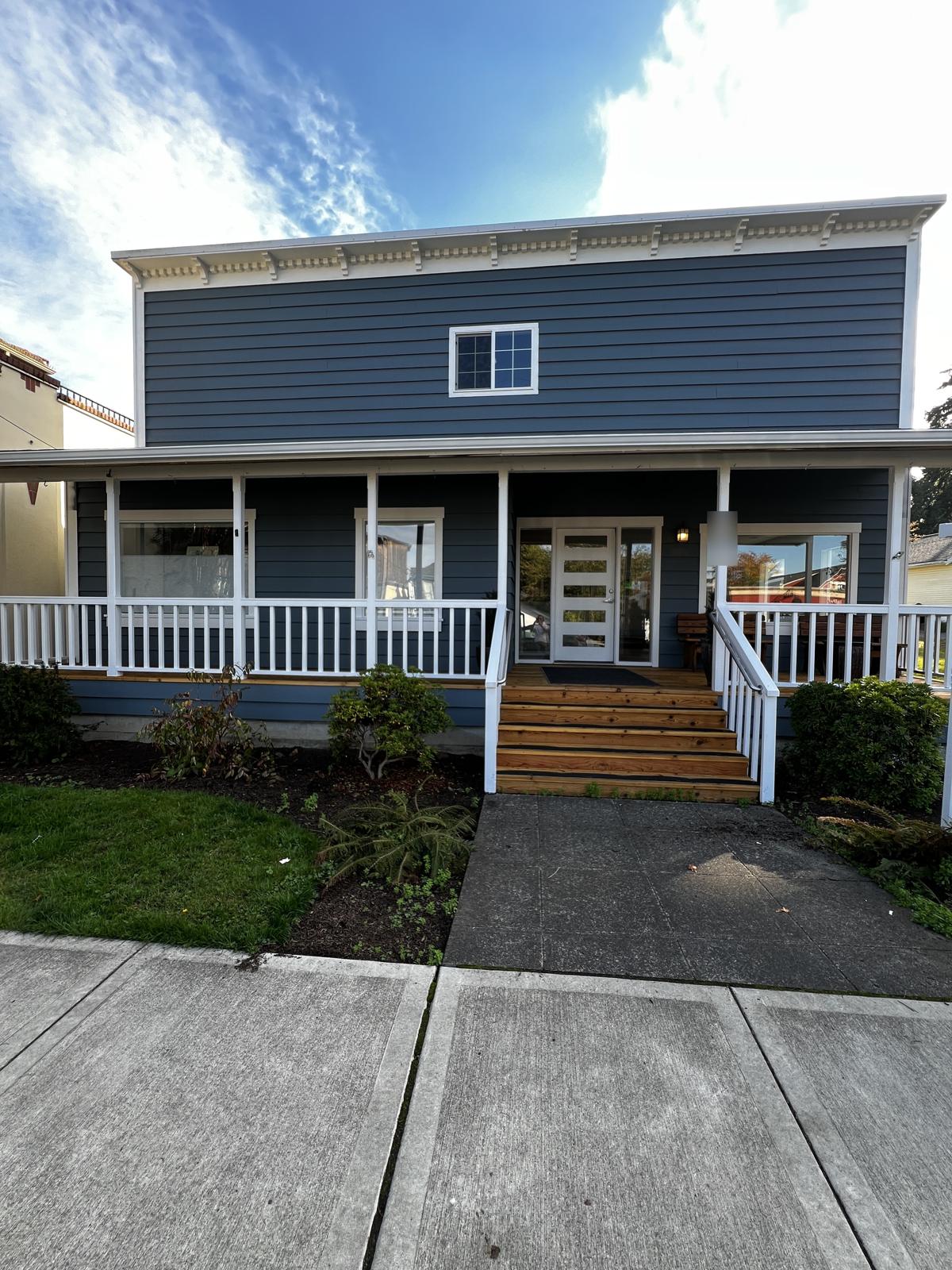 Commercial office building with blue siding, white porch rails and cornice