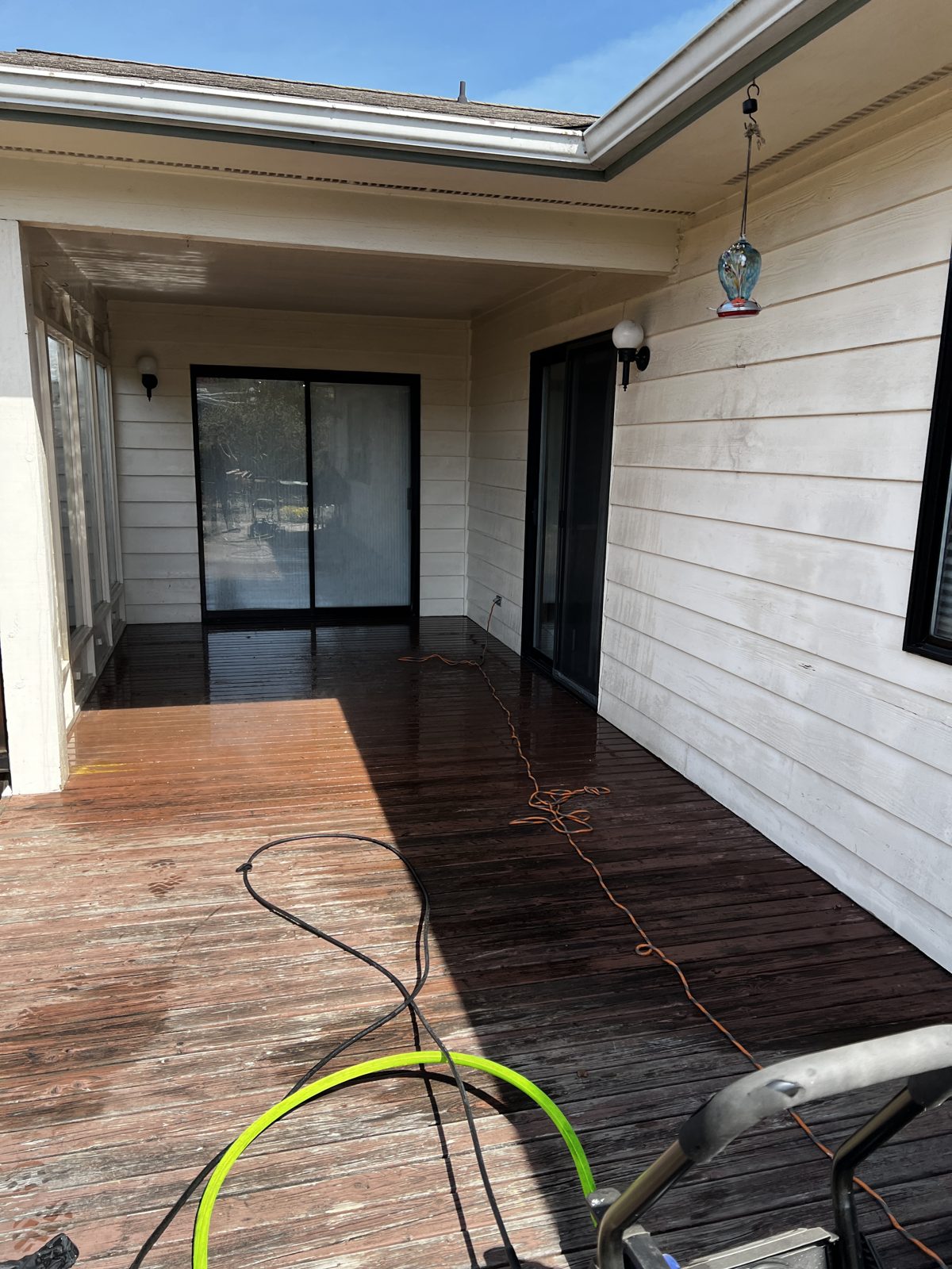 Wood deck being pressure washed on a covered patio