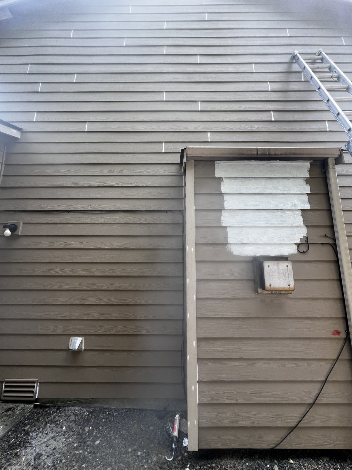 Repaired siding boards primed white before painting