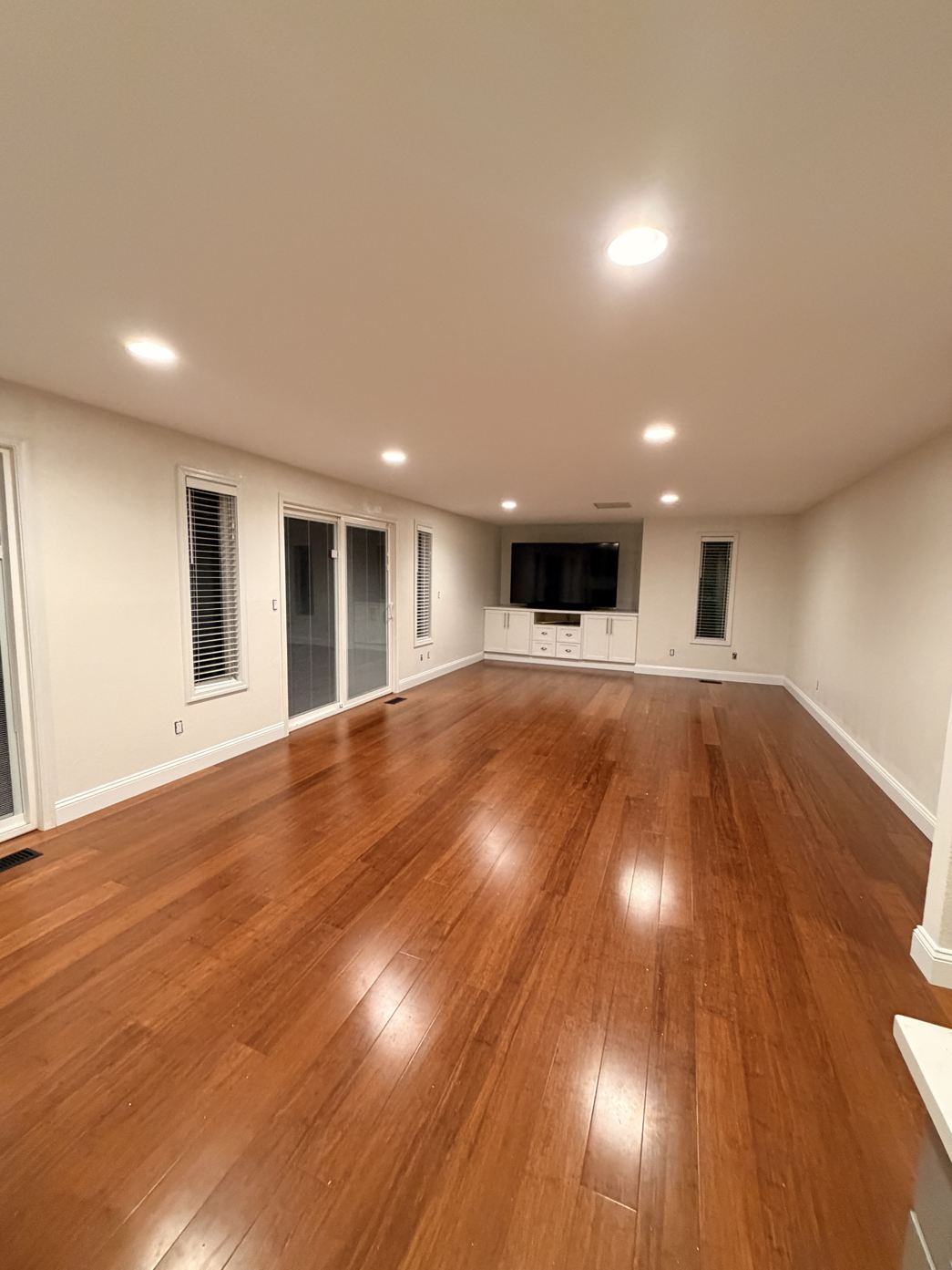 Long living room freshly painted in warm white with wood floors