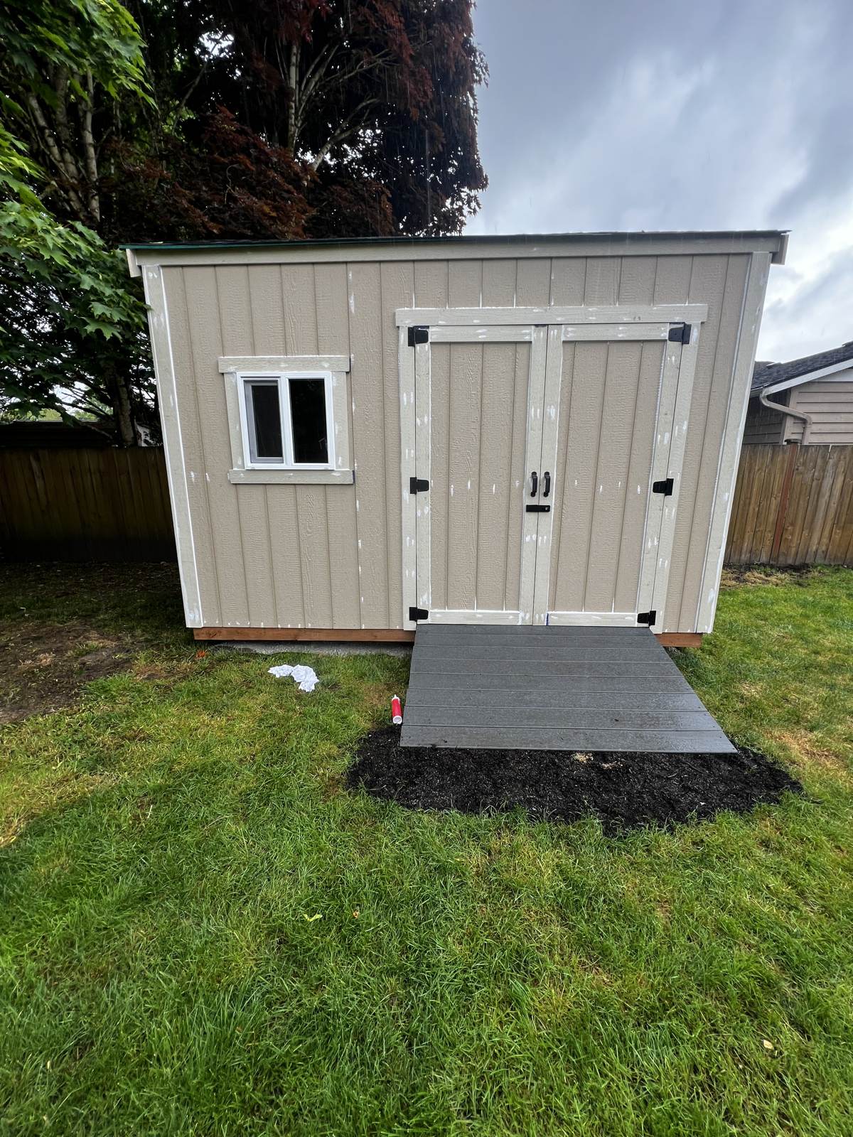 Backyard shed painted with white trim and doors