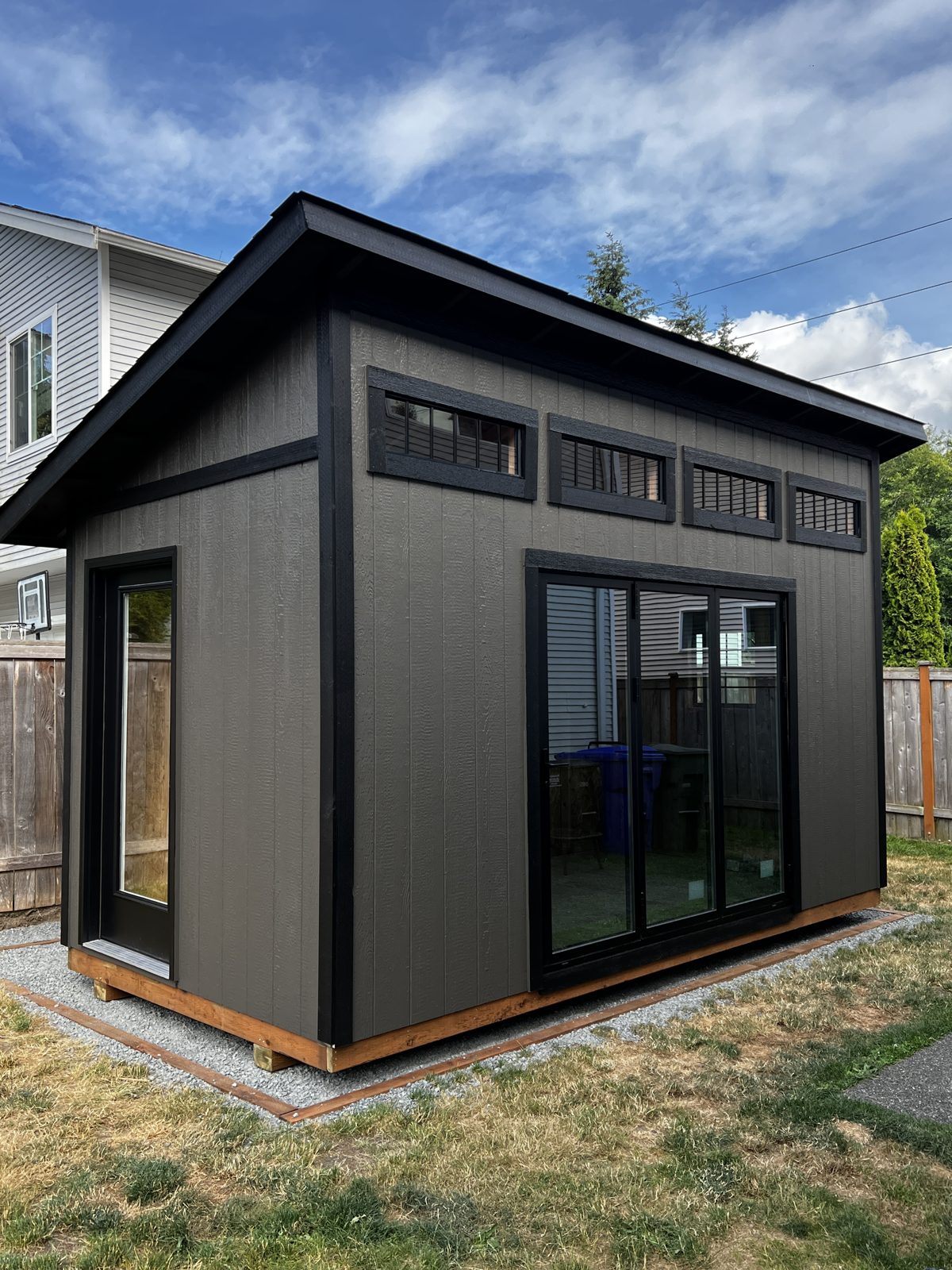 Backyard studio painted black with a cedar base