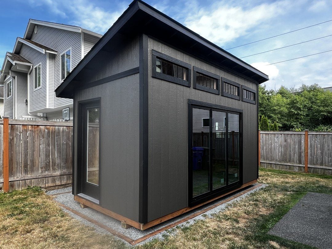 Modern backyard studio in Mukilteo painted black with a cedar base