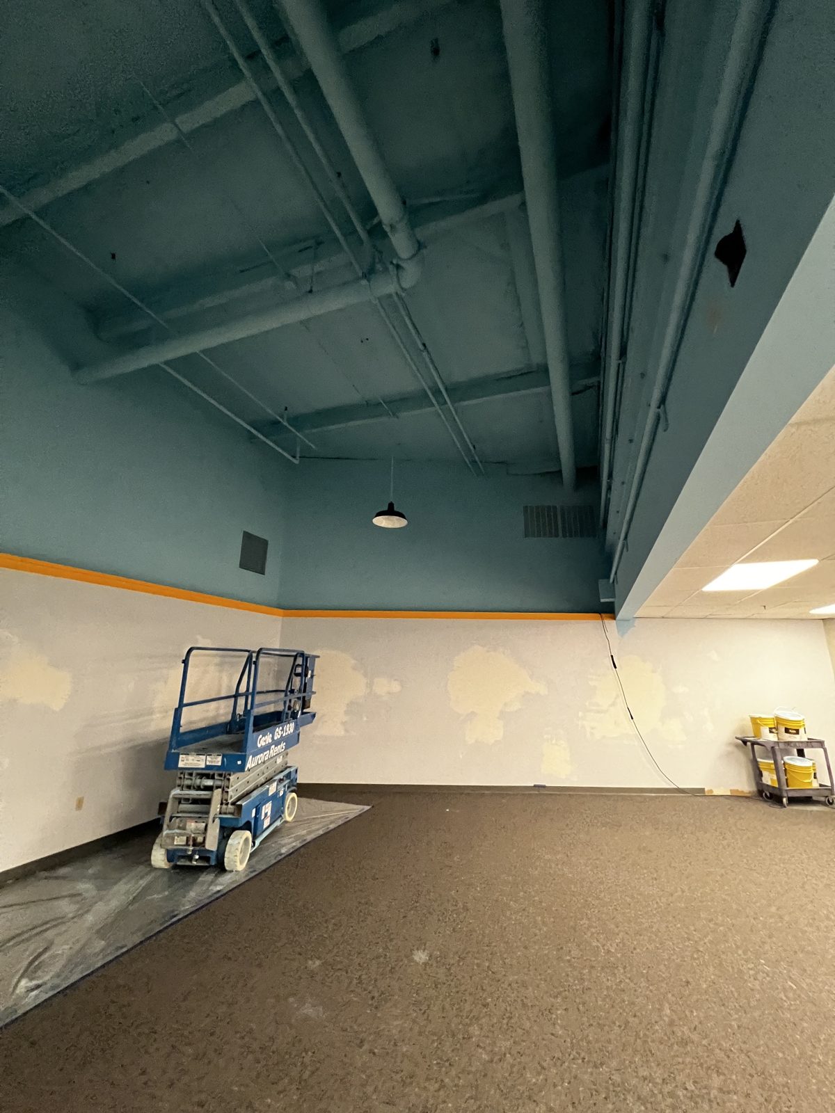 Church in Bothell with its high open ceiling repainted teal, with a scissor lift in the room