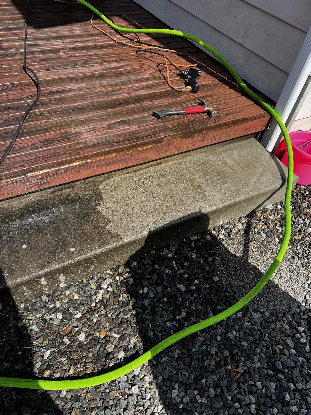 Concrete step half pressure washed, showing clean concrete next to dirty concrete